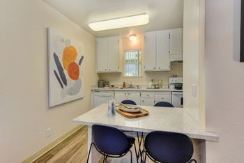 Dining area with white counters and two blue chairs overlooking the kitchen. White cabinets and appliances in the kitchenat Renaissance Park Apartments, Davis